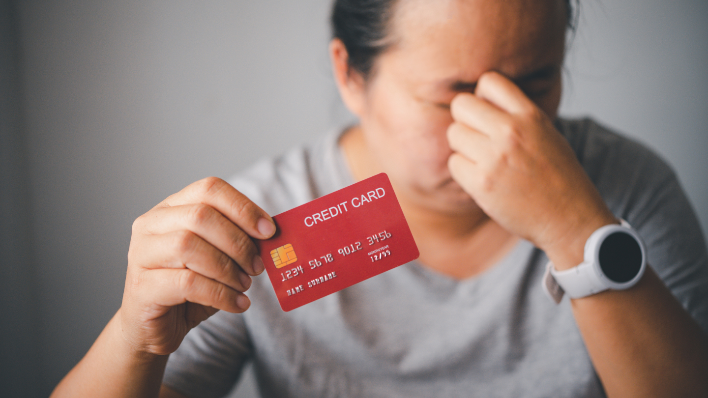 Mujer estresada mostrando su tarjeta de crédito